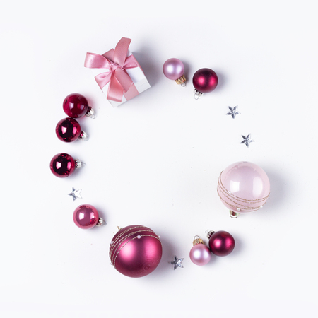Christmas flat lay round frame with pink abd violet glass balls and gift box, copy space on white deskの写真素材