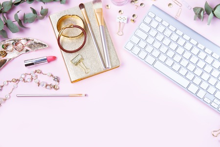 Flat lay home office workspace - white modern keyboard with female accessories and jewellery, copy space on pink backgroundの写真素材