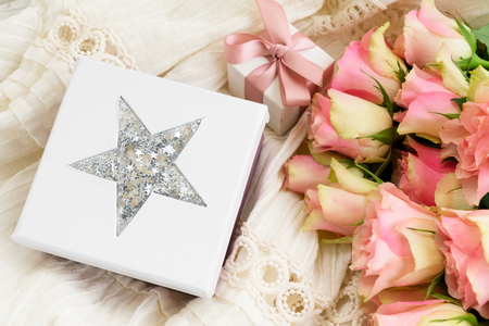 Pink roses bouquet with gift box on laced wedding dress backgroundの写真素材