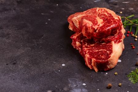 Raw beef steak with pepper and garlic on dark stone background with copy spceの写真素材