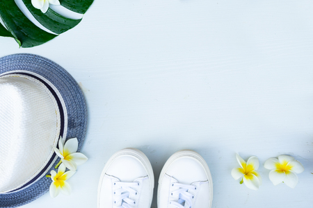 Summer flat lay scene with hat and green leaves on gray background with copy spaceの写真素材
