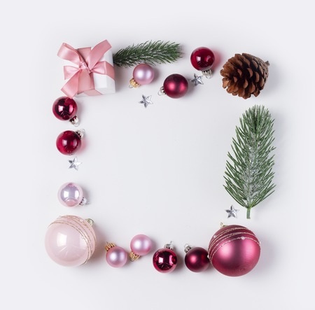 Christmas flat lay frame with pink abd violet glass balls and gift box, copy space on white deskの写真素材