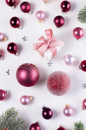 Christmas flat lay pattern with pink abd violet glass balls and gift box on whiteの写真素材