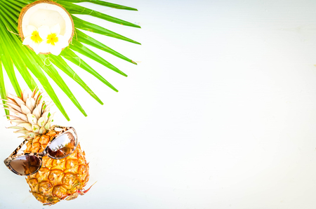 Summer flat lay scene with funny pineapple friut and tropical leaves, summer travel vacation concept, tonedの写真素材
