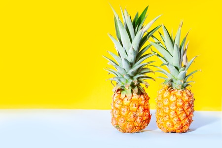 Two pineapple friuts on bright yellow background