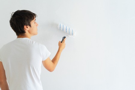 Young men painting wall of her house, do it yourself home renovation conceptの写真素材