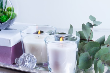 Natural eco home close up decor with green leaves and burning candles on metal trayの写真素材