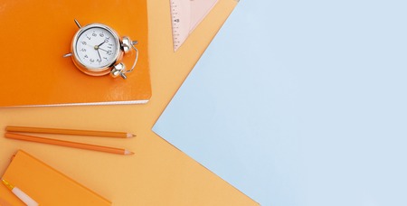 Back to school styled scene with school supplies on blue and orange background bannerの写真素材