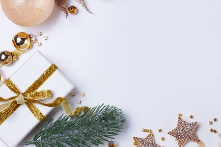 Christmas flat lay scene with golden decorations and git box, copy space on white deskの写真素材