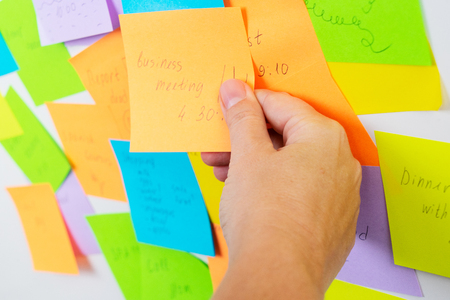 To do list - multicolored task notes with hand choosing one close up