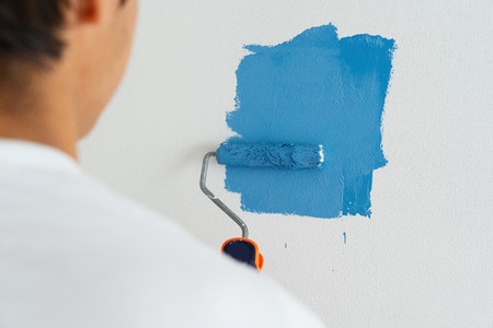 man painting wall in blue color in the white roomの写真素材