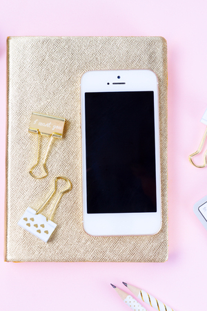 Home office desk with modern white phone on pink backgroundの写真素材