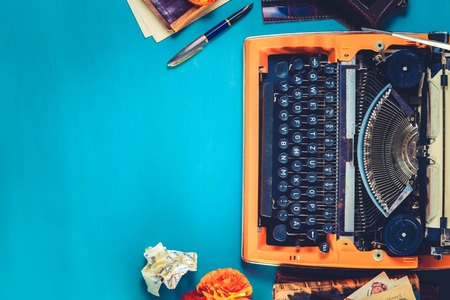 Workspace with orange vintage typewriter, copy space on blue background, flat lay scene, tonedの写真素材
