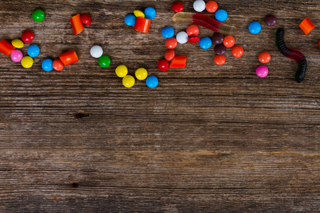 Colorful candies pile on wooden background flat lay scene border with copy spaceの写真素材