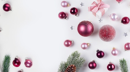 Christmas flat lay banner with pink abd violet glass balls, fir tree twigs and gift box, copy space on white deskの写真素材