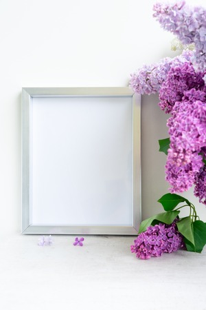 Fresh lilac flowers with empty frame on white tableの写真素材