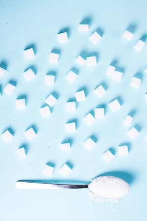 Sugar cubes and spoon with crystalines on blue background, flat lay sceneの写真素材