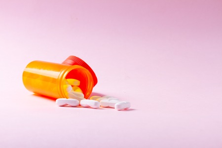 White pills in orange bottle on pink  with copyの写真素材