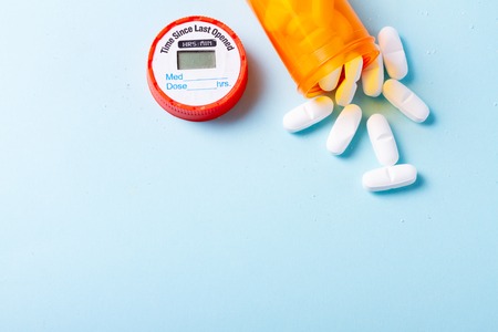 White pills in orange bottle on blue  with copy spaceの写真素材