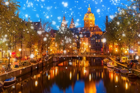 Church of St Nicholas over old town canal illuminated at night with snow, Amsterdam, Hollandの写真素材