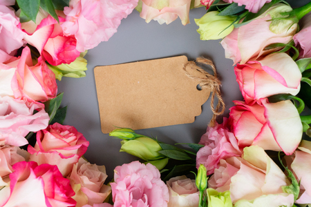 Rose fresh flowers on gray table from above, flat lay scene with copy space on paper noteの写真素材