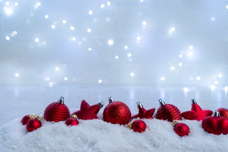Christmas scene with snow - red balls decorations row, lights in backgroundの写真素材