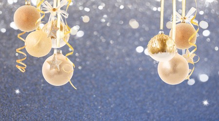 Hanging golden christmas balls on dark silver bokeh background with copy space