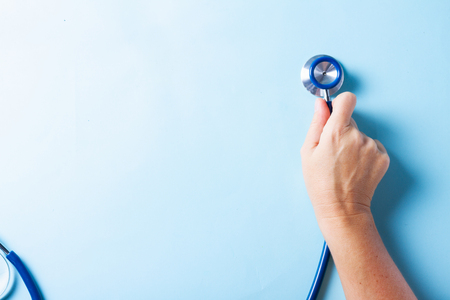 Healthcare concept - hand holding stethoscopee on blue backgroundの写真素材