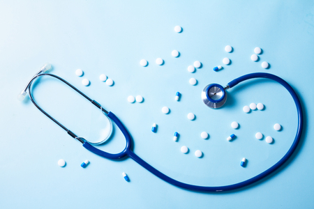 Healthcare concept - stethoscope and white pills on blueの写真素材