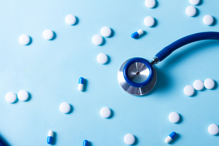 Healthcare concept - stethoscope and white pills on blue backgroundの写真素材