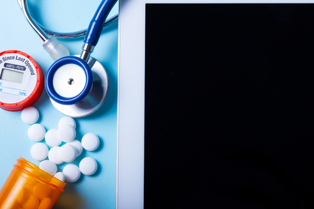 Pile of medical pills with tablet screen on blue backgroundの写真素材