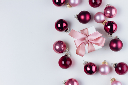 Christmas flat lay scene with pink and violet glass balls and gift box with copy space on whiteの写真素材