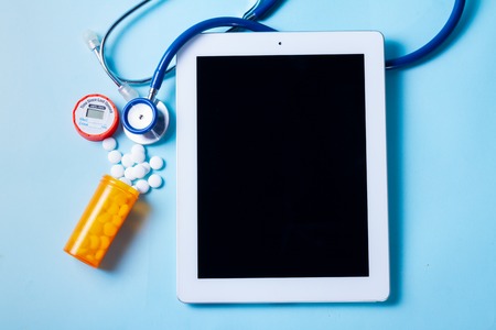 Bottle with medical pills with tablet on blue background