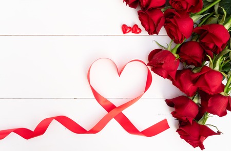 Red roses with heart on white wooden background, top viewの写真素材
