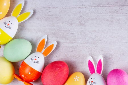 Easter flat lay scene with colored eggs and bunnies, top view