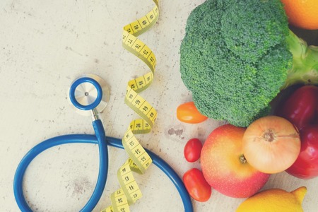 healthy diet concept, raw fresh vegetables with stethoscope on white wooden tableの写真素材