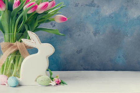 fresh tulip flowers in vase with easter bunny on gray background with copy space, retro toned