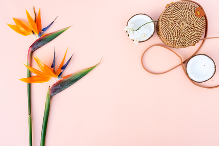 Summer flat lay scenery with tropical flowers, bag and coconuts on pink background with copy spaceの写真素材
