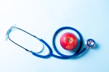 Healthcare concept - stethoscope and red apple on blueの写真素材