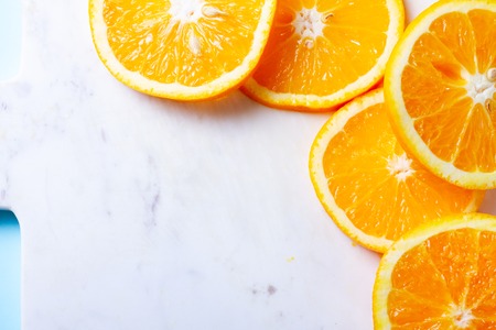 Orange fruit slices on white marble cutting board with copy spaceの写真素材