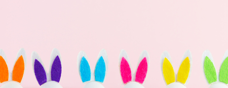 Row of funny easter bunnies ears on pink  banner with copy spaceの写真素材