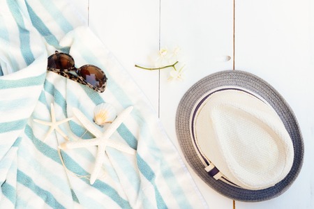 Summer flat lay scenery on white wooden background with summer towel and hatの写真素材