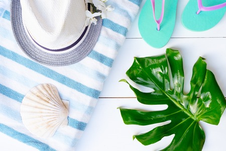 Summer flat lay scenery on white wooden background with blue flip flops and hatの写真素材