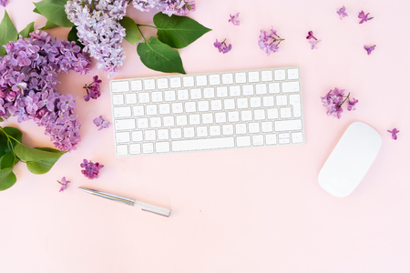 Flat lay top view home office workspace - modern keyboard with lilac flowersの写真素材