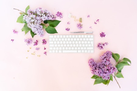 Flat lay home office workspace - modern keyboard with lilac flowers and copy spaceの写真素材