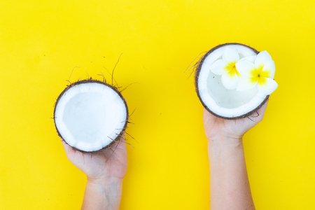 someone hands holding coconut cut open fruit on yellow backgroundの写真素材