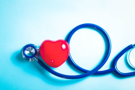 Healthcare concept - stethoscope and red heart on blue background, top view, toned