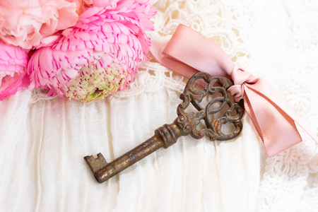antique rusty skeleton key with bow and pink ranunculus bouquetの写真素材
