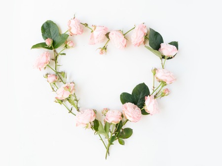 Floral wedding composition. Heart frame made of pink rose and ranunculus flowers on white background. Flat lay, top view, copy spaceの写真素材