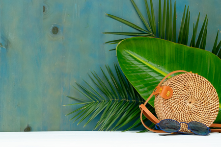 Summer scenery with straw bag and tropical leaves, copy space on backdropの写真素材